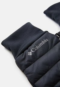 Črna pufasta brezrokavnik z gladko zunanjostjo, puhastej teksturo in sivo Columbia oznako. Ima oblazinjeno ovratnico in nastavljive sponke.