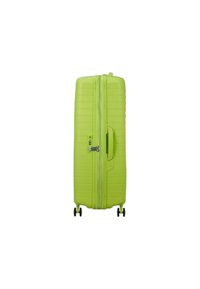 Valigia rigida verde con superficie testurizzata, scanalature verticali, maniglia superiore, chiusura con zip e due ruote per la mobilità.