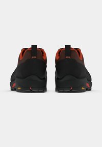 Μαύρα και πορτοκαλί παπούτσια για μονοπάτια με πλέγμα στο πάνω μέρος, πίσω τμήματα και σόλες από καουτσούκ Vibram. Διαθέτουν αεροδυναμικό σχεδιασμό και υφασμένους λεπτομερείς διακοσμητικούς χαρακτήρες.