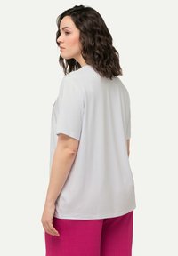 Camiseta blanca de manga corta con escote redondo, con una textura suave y un ajuste holgado, combinada con pantalones texturizados de un vibrante color rosa fucsia.