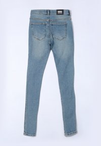 Jeans skinny de denim azul con una textura suave, cinco bolsillos y una etiqueta en la cinturilla de color negro. El diseño cuenta con un lavado de denim clásico.