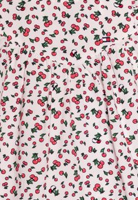 Tessuto bianco con un motivo ripetuto di ciliegie e foglie in rosso e verde. Presenta pieghe arricciate per texture e fluidità.