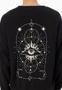 Zwarte sweatshirt met een witte grafische afbeelding van een oog omringd door hemelse motieven, waaronder sterren en manen, met ingewikkelde details.