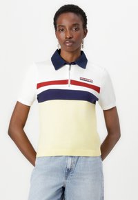 Kortærmet polo shirt i gul med marineblå krave. Har vandrette striber i rød og marineblå. Inkluderer zip-lukning og logo-detalje.