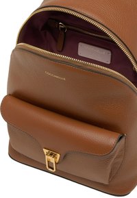 Zaino in pelle marrone dalla forma strutturata, con una cerniera dorata, una tasca con patta e una fodera interna color bordeaux con una tasca interna con cerniera.