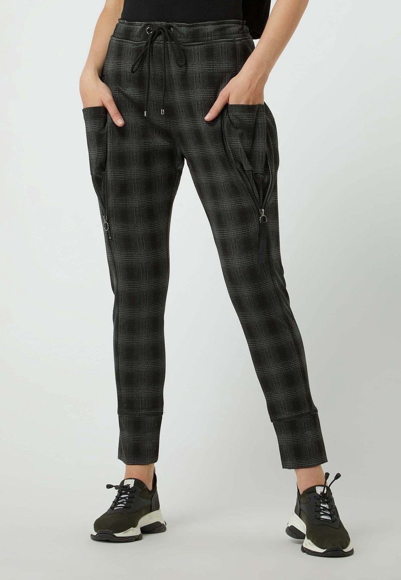 Svart- och grårutig joggingbyxor med elastisk midja, dragsko, sidofickor med dragkedja och smalnande muddar. Materialet verkar mjukt och texturerat.