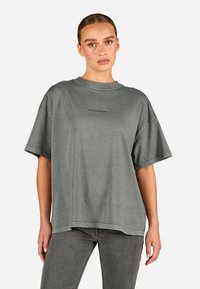 Pelēka liela izmēra t-kreklu, kas izgatavots no mīksta auduma, ar apaļu kakla izgriezumu un īsām piedurknēm. Priekšpusē redzams uzraksts "PEGADORES".