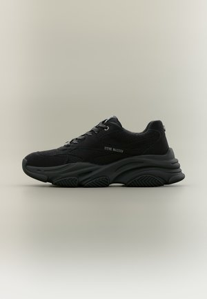 Черна маратонка Steve Madden с дебела скулптирана подметка, мрежест и велурен горен слой, връзки и брандирана странична детайл на неутрален фон.