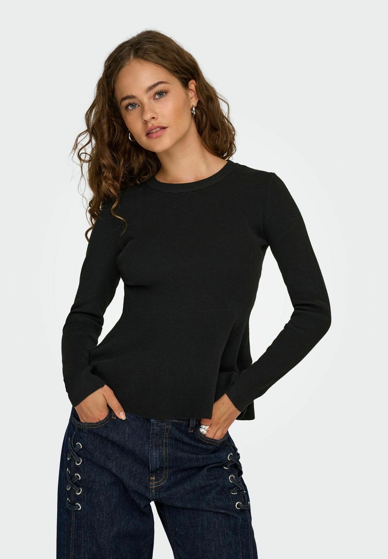 Maglietta nera a coste a maniche lunghe con scollatura rotonda. Abbinata a jeans di denim scuro con dettagli in pizzo sui lati e tasche frontali.