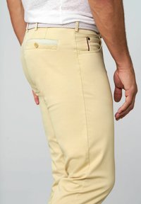 Beige dressbroek met een slim fit, voorzien van een geweven riem, achterzak met knoopsluiting en stikseldetails. Soepele textuur.