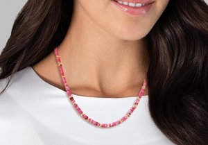 Collana di perline rosa con perline rettangolari decorate con accenti dorati. Indossata su un indumento bianco, mette in risalto una finitura liscia e lucida.