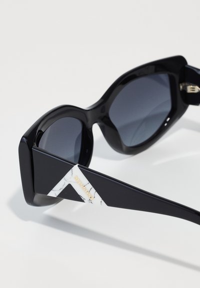 Black oversized sunglasses with dark lenses, featuring a white and marble-patterned accent on the temple, branded with "Missoni" in gold.