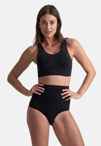 Zwarte sportbeha met brede banden, naadloos ontwerp en rekbare stof, gecombineerd met hoge zwarte onderbroek. Gladde textuur, geen patronen.