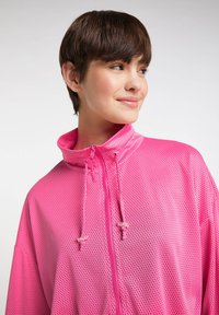 Lettet, åndbar pink zip-jakke med st�åkrave, der har et prikket mesh-design og justerbare snore i halsen.