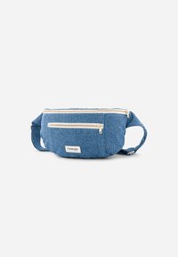 Sac banane en denim bleu avec deux poches zippées à l'avant, sangle réglable et une petite étiquette de logo. Texture douce et forme arrondie.