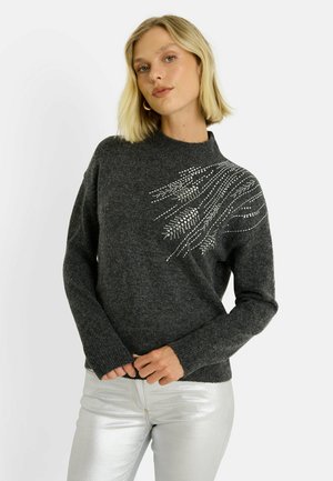 Suéter de punto gris oscuro con cuello alto y mangas largas, con adornos plateados en un patrón de onda en un lado.