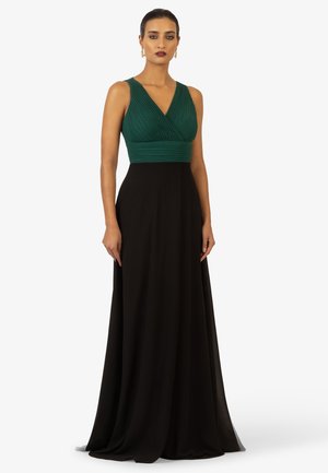Langes Abendkleid mit einem gefalteten, smaragdgrünen Oberteil und einem fließenden schwarzen Rock. Das Kleid hat einen tiefen V-Ausschnitt und ist ärmellos.