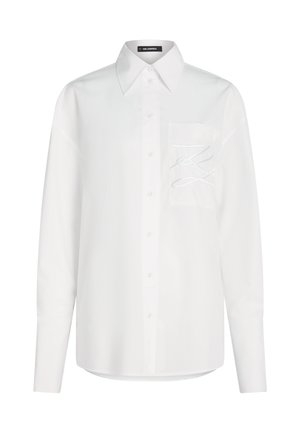 Hvit langermet skjorte med knapper, spiss krage og brystlomme med diskret brodert design.