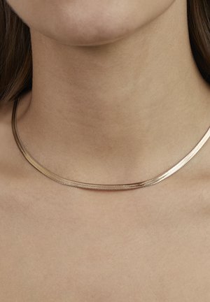 Halskæde i guldfarvet metal med et glat, fladt og fleksibelt design. Har en diskret glans og en sammenlåst kædelinkstruktu, der hviler mod bar hud.