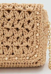 Woven beige handbag made of braided material with a textured finish, featuring gold-tone studs and a chain strap.