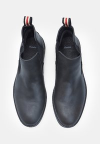 Botine negre din piele, cu laterale elastice, suprafețe texturate, vârfuri rotunjite și cili cu dungi. Talpa flexibilă și detalii minime de cusătură.