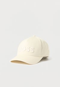 Kapa za baseball iz kremastega blaga z ukrivljenim ščitnikom. Na sprednji plošči je v izbočenih črkah napis "BOSS" v enaki barvi.