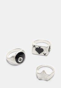 Set di tre anelli: uno con una biglia nera smaltata a forma di otto, uno con il simbolo di un asso di cuori e un anello argento a forma di stella.