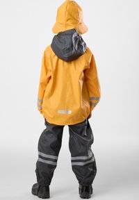Gul vattentät jacka med grå huva, kombinerad med grå vattentäta byxor med reflexsträck. Designad för barn, hållbart material.