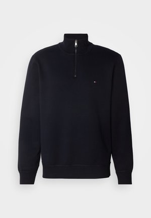 Marineblå sweatshirt med kvart lynlås lavet af blødt stof, med et lille logo på brystet, ribbede manchetter og en struktureret krave.