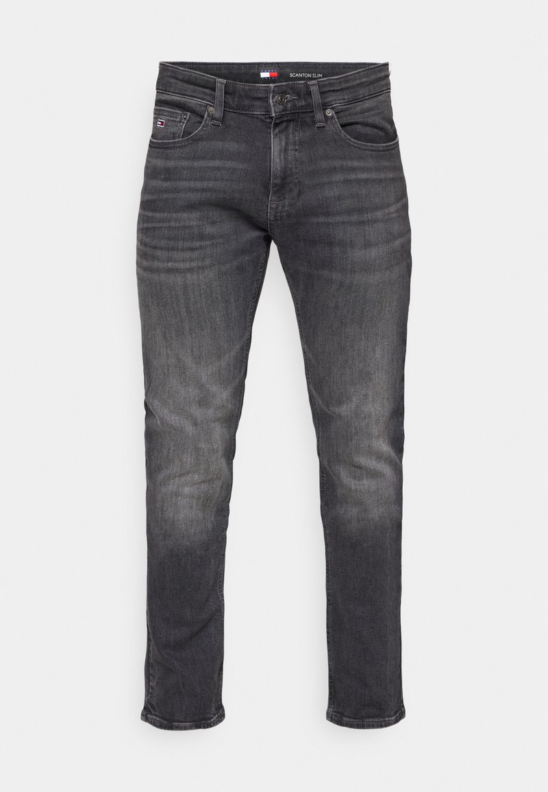 Jeans oscuros de corte slim con una textura desgastada, cinco bolsillos y un logo en la cinturilla. Color uniforme con variaciones sutiles en toda su extensión.