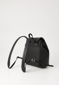Schwarzer Leder-Rucksack mit strukturiertem Design, verstellbaren Trägern und einem goldfarbenen Schnallen-Akzent. Glatte Textur und runde Form.