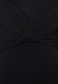 Tissu noir avec un détail de nœud torsadé créant des plis doux et de la texture au centre.