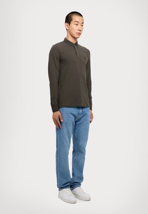 Polo shirt a maniche lunghe verde scuro con colletto, abbinato a jeans azzurri e sneaker bianche. Design minimalista con un piccolo dettaglio del logo.