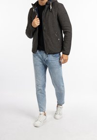 Grå fleece zip-up jacka med huva, har kontrasterande innertyg, sidofickor och dragsko-accenter, ihopparad med ljusblå jeans och vita sneakers.