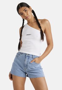 White, one-shoulder ribbed tank top with black RVCA logo, paired with light blue denim shorts with frayed hem and cuffed waist.