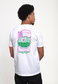 Hvid bomulds T-shirt med et farverigt grafisk design, der viser en skål ramen med spisepinde, i pink og grøn på ryggen.