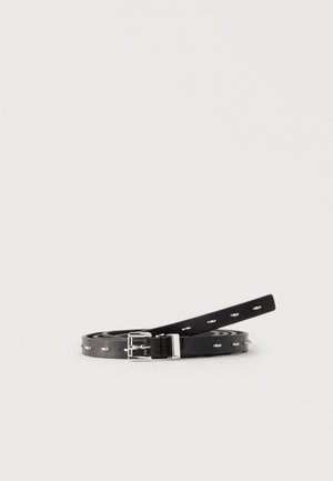 Μαύρη στενή δερμάτινη ζώνη τυλιγμένη με ασημένια αγκράφα και οβάλ μεταλλικά ανοίγματα σε λευκό φόντο.