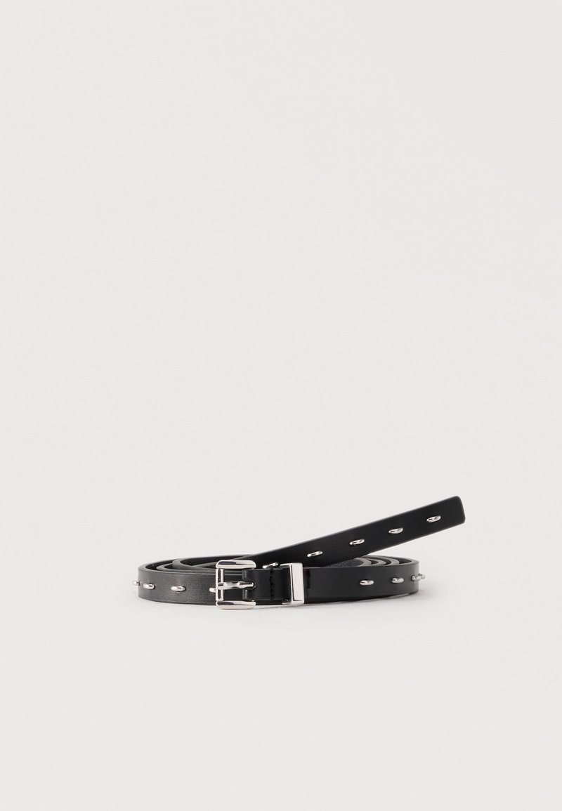 Μαύρη στενή δερμάτινη ζώνη τυλιγμένη με ασημένια αγκράφα και οβάλ μεταλλικά ανοίγματα σε λευκό φόντο.