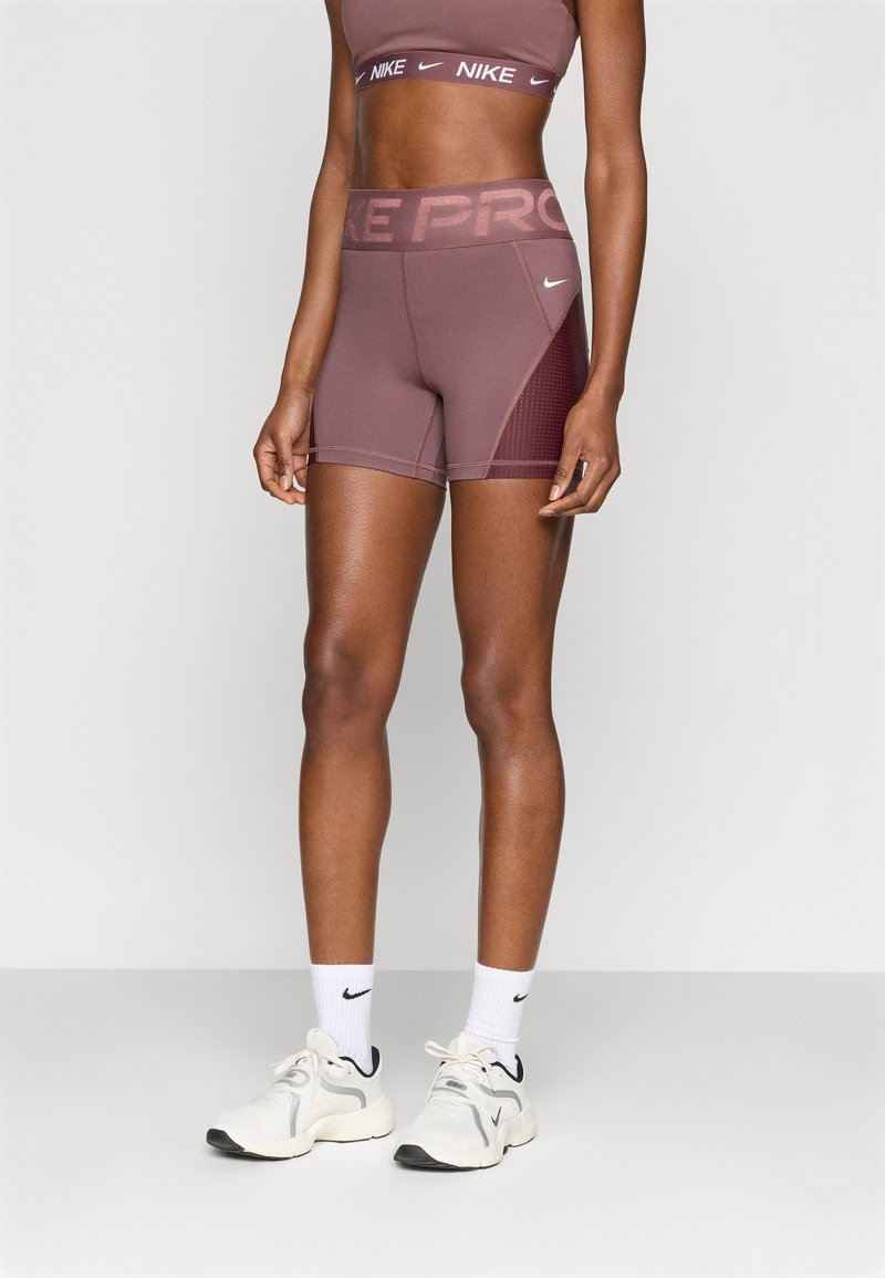 Αθλητικό σουτιέν Nike Pro και αντίστοιχα σορτς σε απαλή απόχρωση μουβ, με υφασμάτινη επένδυση και λογότυπα της μάρκας σε αντίθετα χρώματα.