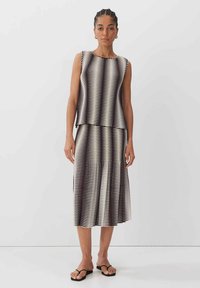 Top senza maniche a strisce bianche e nere e gonna coordinata, realizzati in tessuto leggero, presentano un design plissettato con una sottile texture.