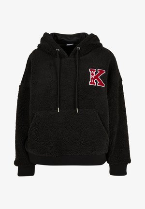 Črna flis jakna s teksturirano površino, kenguru žepom, nastavljivimi vrvicami in rdečim vezenim črkem "K" na sprednji strani.