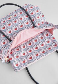 Tryckt ryggsäck med rosa tyg som har ett upprepat mönster av katter och rosor, svarta remmar och ett fodrat inre med dragkedja.