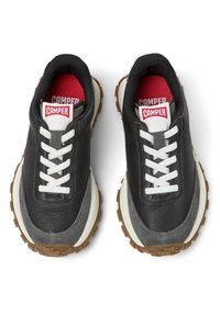 Sneaker in pelle nera con accenti bianchi e grigi, dotate di una suola testurizzata, punta rotonda, lacci bianchi e un logo rosso CAMPER sulla linguetta.