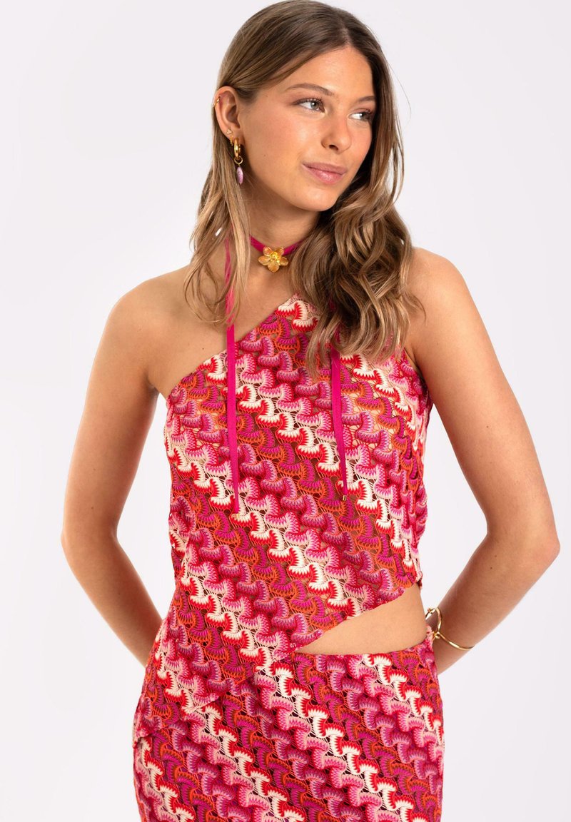 Top de cuello halter que presenta un vibrante patrón rosa con detalles en blanco y rojo en contraste, diseño con cortes y tirantes finos.