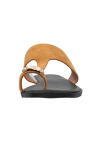 Bruine suède instapsandalen met een brede bovenkant, een zwarte zool en een gouden accent bij de hiel. Soepele textuur en minimalistisch ontwerp.