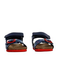 Paio di sandali per bambini blu e rossi con motivi a stella, con cinturini regolabili, plantari in sughero e suole rosse brillanti, visti frontalmente.