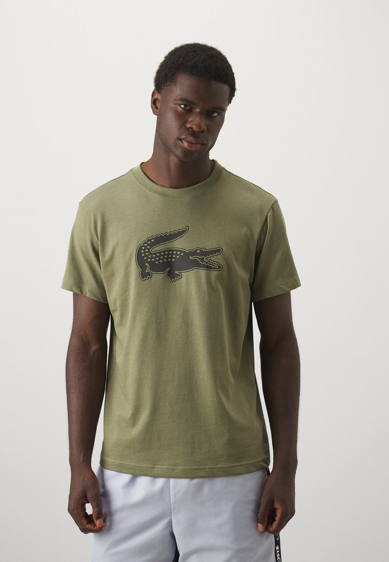 Khaki groene katoenen t-shirt met een zwarte krokodillengrafiek op de voorkant. Klassieke ronde halslijn met korte mouwen en een ontspannen pasvorm.