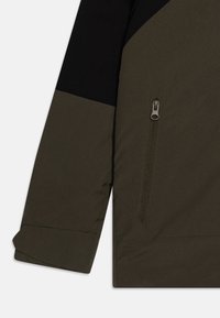 Veste vert olive avec des accents noirs, dotée d'une poche zippée et d'un poignet replié. Texture lisse et design moderne et anguleux.