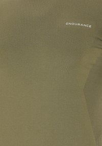 Oliivinvihreä urheilupaita, jossa on teksturoitu yläosa, sileä alaosa ja valkoinen "ENDURANCE"-logo rinnassa.