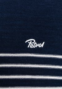 Donkerblauwe gebreide stof met witte horizontale strepen. Borduurwerk van het "Petrol"-logo in het wit aan de bovenlinkerzijde, wat een schone uitstraling creëert.